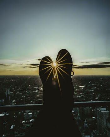 Silhouette of Person's Feet Leaning on Railings during Golden Hour