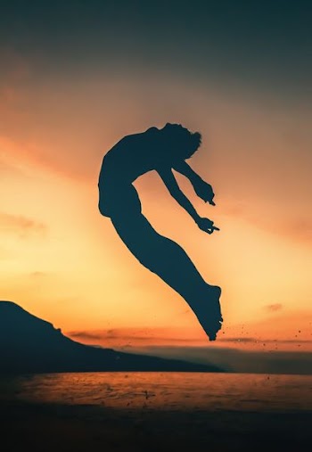 silhouette of person jumping on seashore