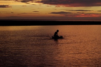 Silhouette of Person on Body of Water during Sunset
