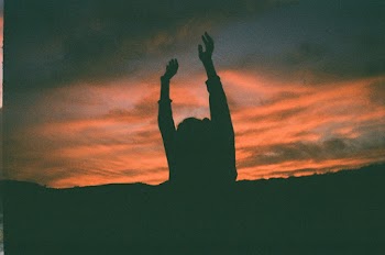 Silhouette of Person Raising Hands Under Golden Hour