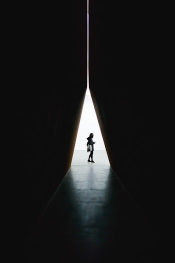Silhouette of Person Standing Between Triangular Building