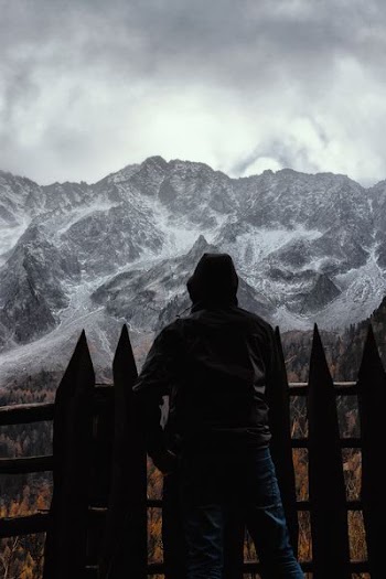 silhouette of person standing in front fence with a scene of mountains