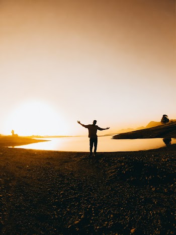 Silhouette Of Person Standing Near Body Of Water During Golden Hour