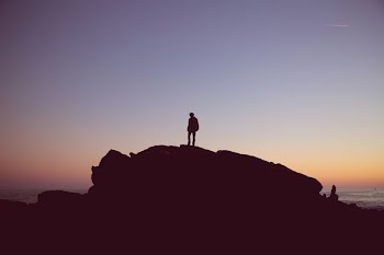 silhouette of person standing on cliff