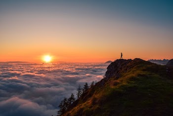 Silhouette Of Person Standing On Cliff During Sunset