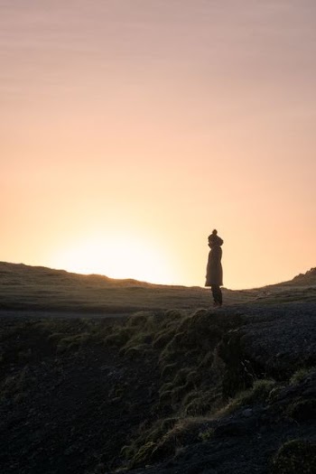 silhouette of person standing on hill during golden hour