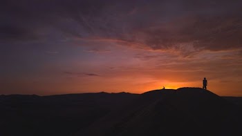silhouette of person standing on hill during golden hour
