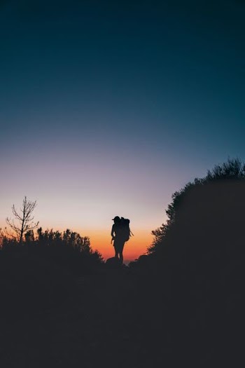 silhouette of person standing on rock