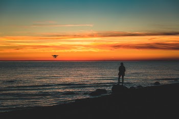 Silhouette of Person Standing on Rock on Seashore