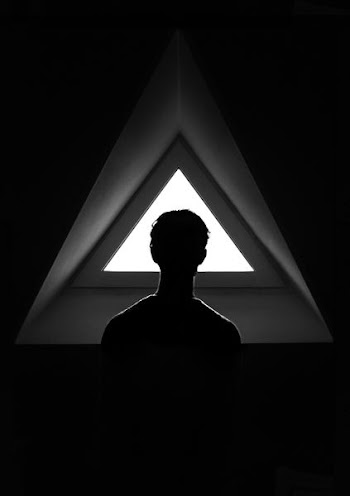silhouette of person standing on triangle window