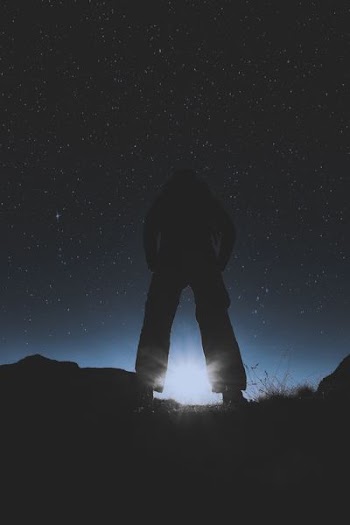 Silhouette of Person Standing Under Starry Night