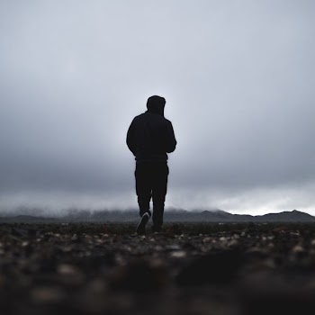 silhouette of person walking in front of mountain