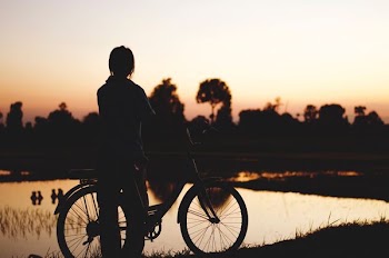 silhouette of person with bicycle near body of water