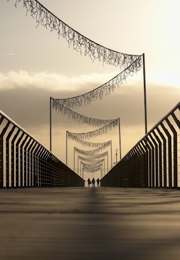 Silhouette Of Three Persons Standing On A Bridge 