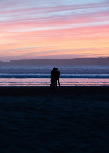 Silhouette of Two People on a Beach During Sunset · Free Stock Photo