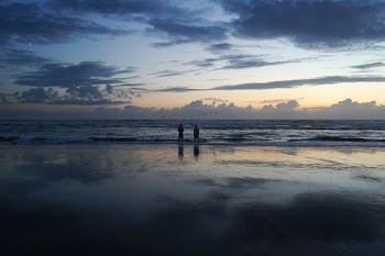 silhouette of two person standing beside seashore