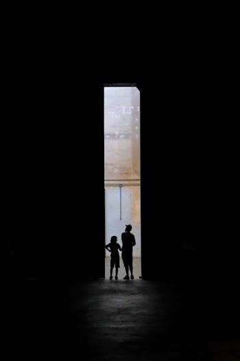 silhouette of two persons standing between doors