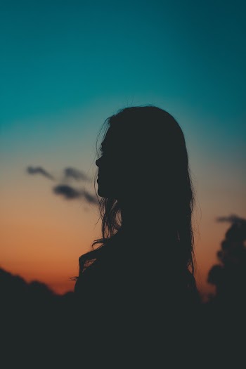 Silhouette of Woman Across Blue and Orange Sky