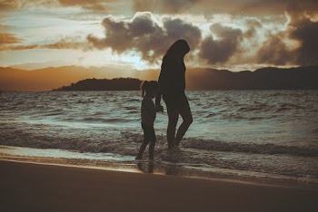 Silhouette Of Woman And Girl Walking On Seashore