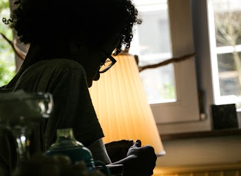 Silhouette of Woman Beside Beige Lampshade Inside White Painted House
