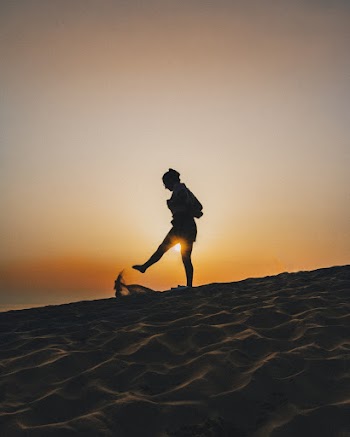 Silhouette of Woman Kicking Sand