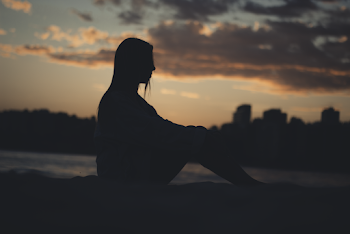 Silhouette of Woman Sitting on Rock