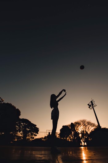 Silhouette of Woman Standing While Raising Both Hands during Night Time