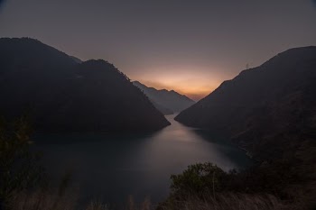 silhouette photo of body of water between mountains