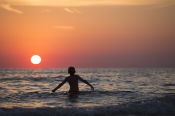 Silhouette Photo of Child on Body of Water during Golden Hour