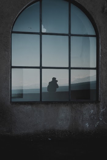 Silhouette Photo of Man Standing Beside Window
