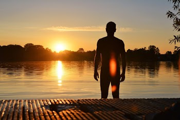 Silhouette Photo of Man Standing Near Lake