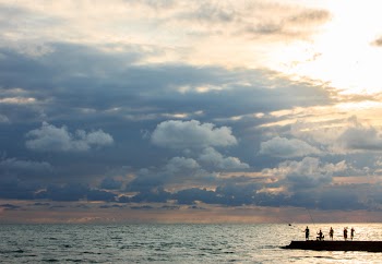 Silhouette Photo of People Standing on Dock Near Sea
