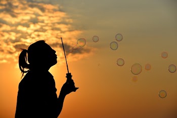 Silhouette Photo of Person Blowing Bubbles during Golden Hour