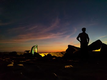 Silhouette Photo of Person Standing Near the Rock