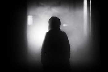 silhouette photo of person standing on door frame