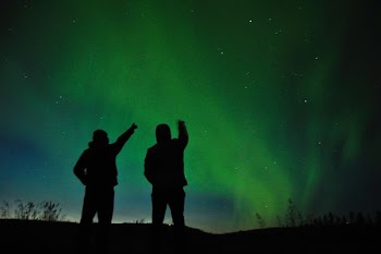 silhouette photo of two person looking up the sky