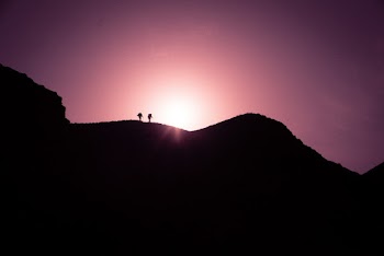 Silhouette Photo of Two Persons Standing on Black Mountain Peak