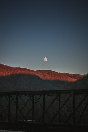 Silhouette Photography of Bridge Under Moon by Day