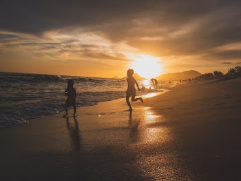 Silhouette Photography of Children Playing Near Body of Water