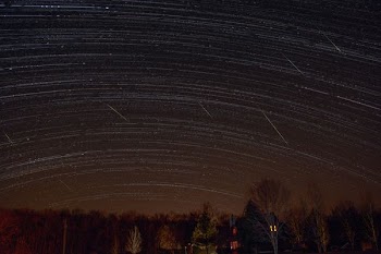 silhouette photography of house under beige sky during meteor shower
