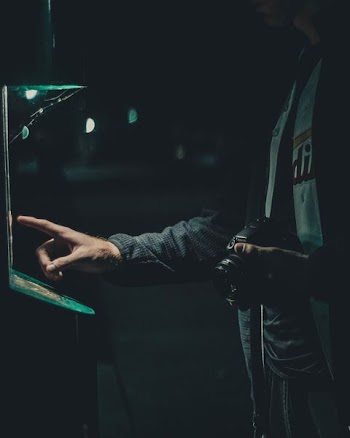 silhouette photography of man holding camera while attempting to operate machine