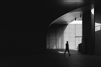 silhouette photography of man walking on floor beside post