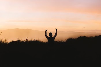 silhouette photography of person racing hands in front of mountain