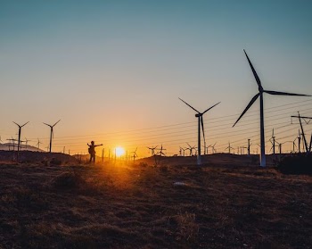 silhouette photography of person standing near windmill
