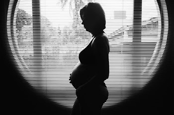 silhouette photography of pregnant woman near window