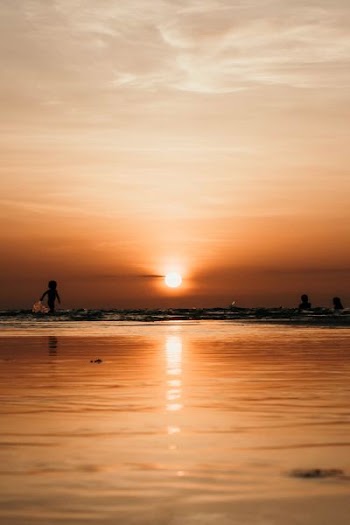 silhouette photography of two person on body of water during sunset