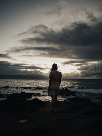 silhouette photography of woman standing near sea waves