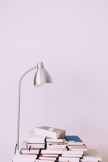 Silver Desk Lamp Near Pile of Books