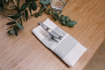 Silver Fork and Knife Inside Gray and White Table Napkin on Table