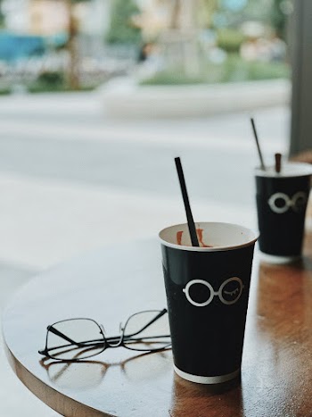 Silver-framed Eyeglasses Beside Black Cups